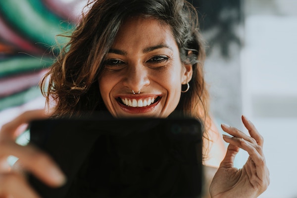 Stock image of woman smiling while using her phone