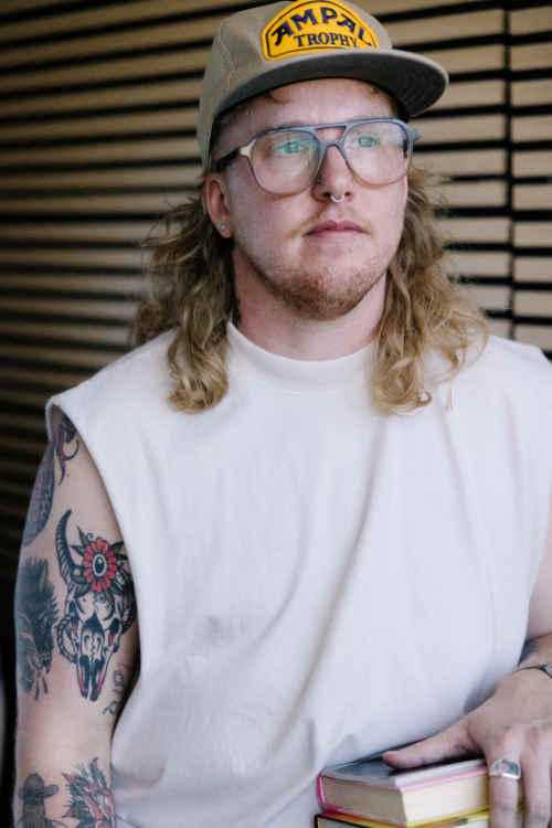 Photo of therapist, River Martone, wearing a white tank top and hat.